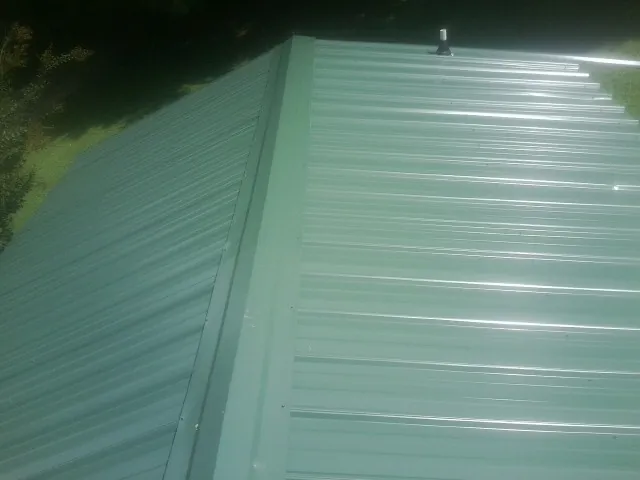 New green metal panels meeting at the ridge of a roof — Flat Roof Repair work by our crew in West Middlesex