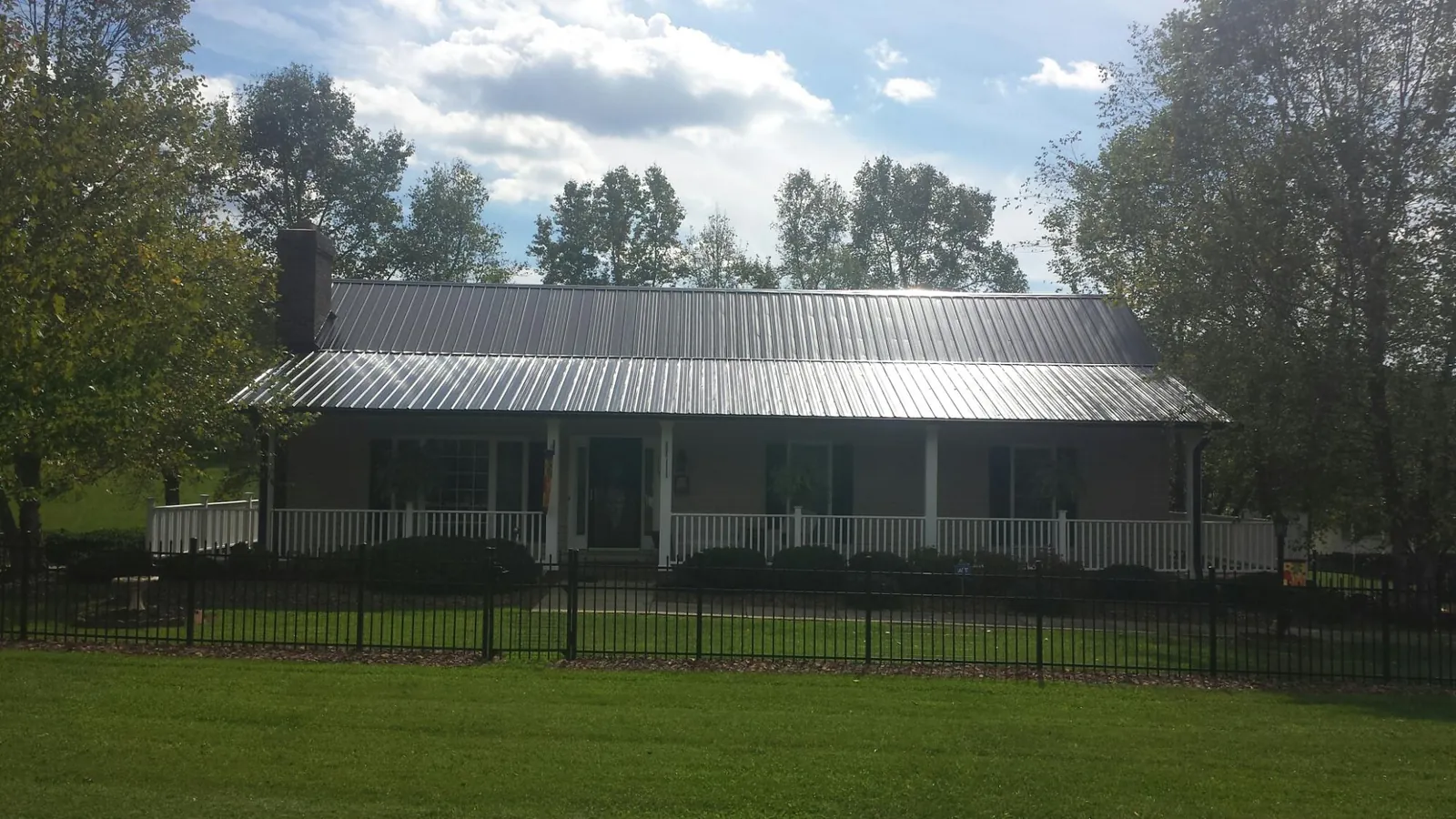 Gray metal roof on a brick ranch with a full width front porch — Gutter Guard Installation work by our crew in West Middlesex