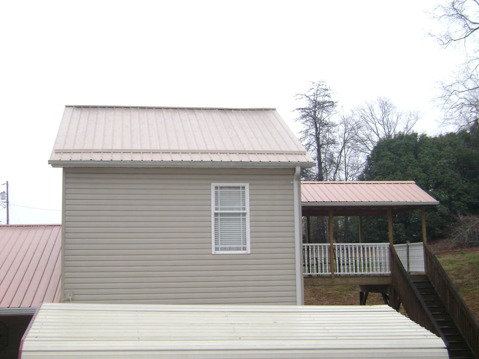 Tan metal roofs on a two story addition and attached porch, from a Roof Replacement job in West Middlesex