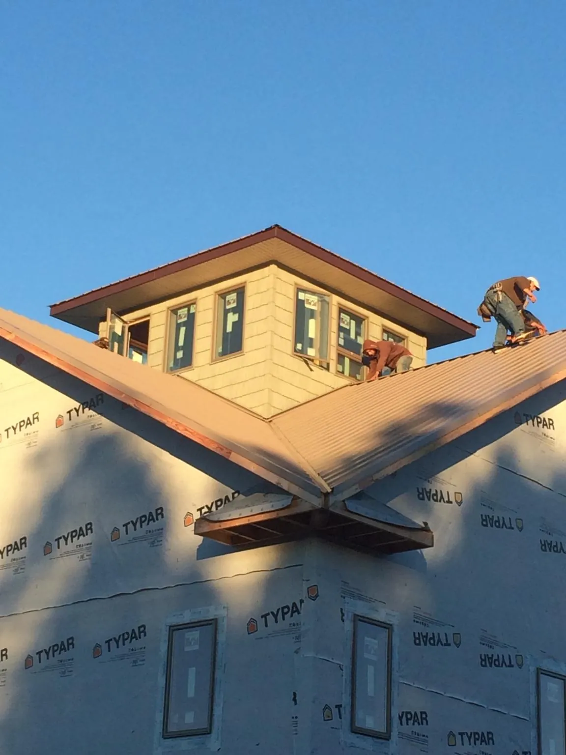 Roofers working around a rooftop cupola on a new metal roof at sunset — Roof Waterproofing in West Middlesex by Roofing Brothers